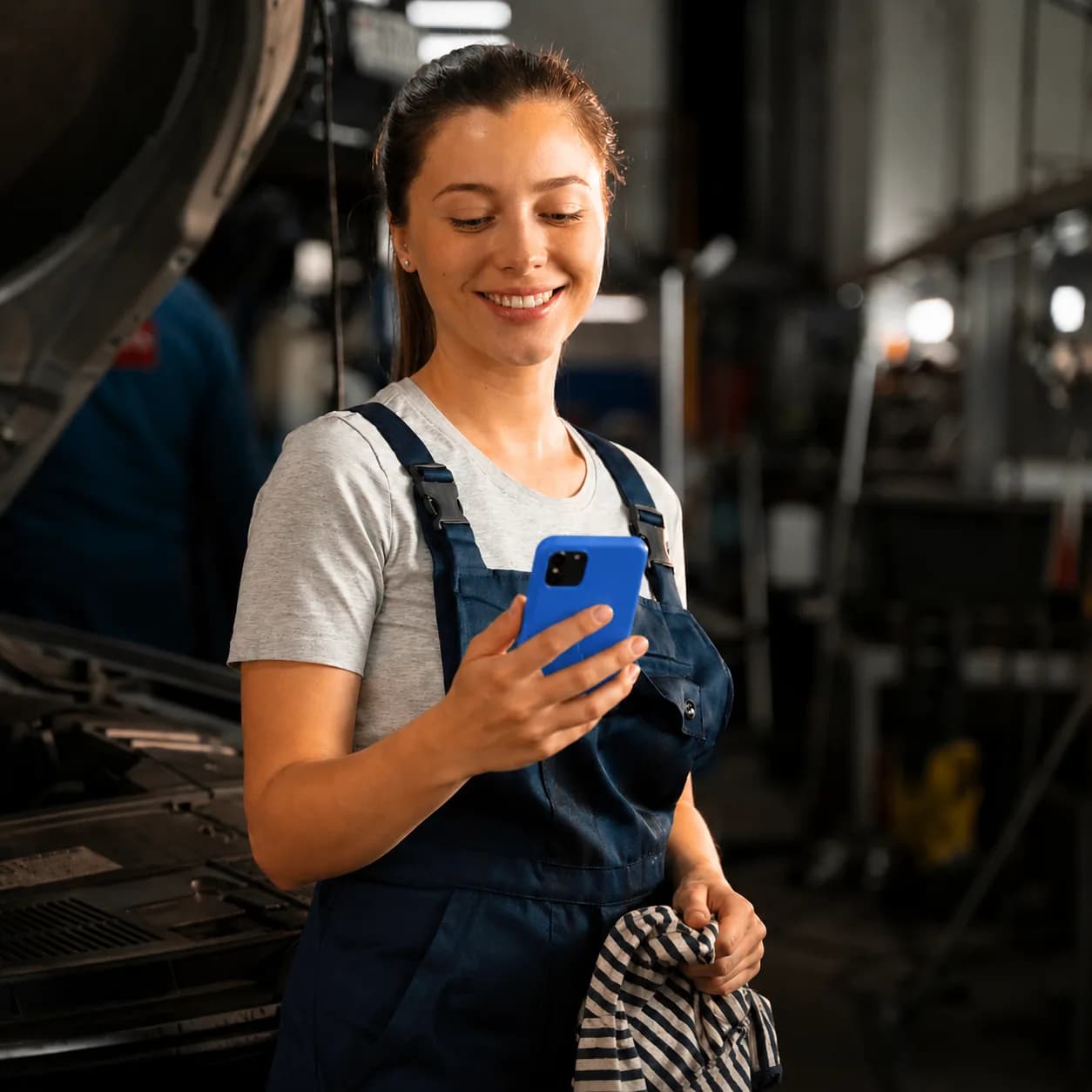 Mulher trabalhadora CLT usando o celular na oficina