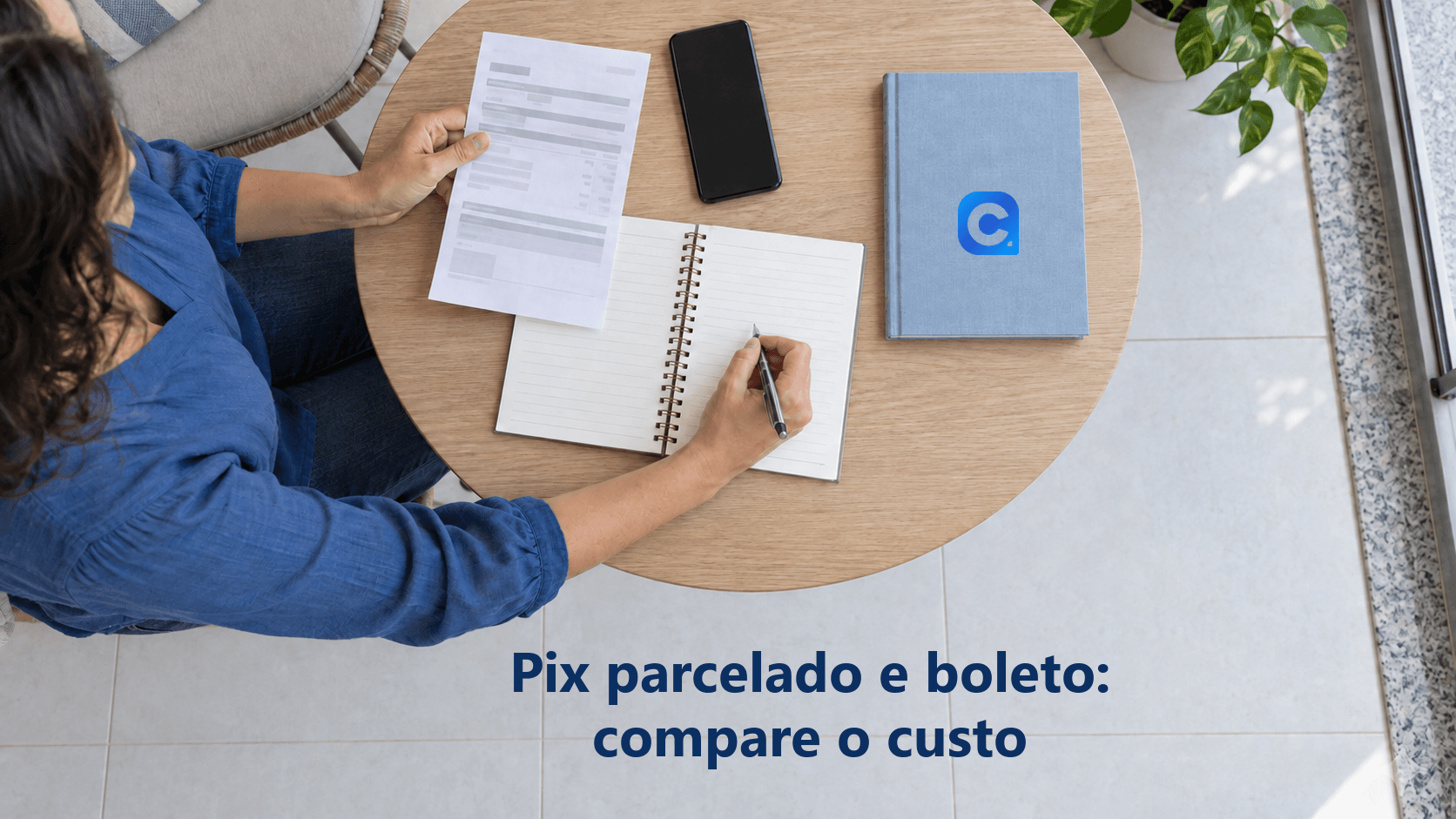 Vista superior de pessoa conferindo uma conta e anotando compromissos em caderno na varanda; celular de tela apagada e caderno azul com o símbolo oficial do Meu Consig estão apoiados na mesa.